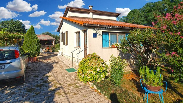 A single-story house with a tiled roof, a small porch, and a garden with various plants and flowers. - House 1461/13494 (Istria - Pula), 4500m from the beach (Pula)