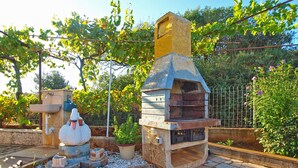 An outdoor stone oven with a chimney, surrounded by a stone-paved area and potted plants. - House 1461/13494 (Istria - Pula), 4500m from the beach (Pula)