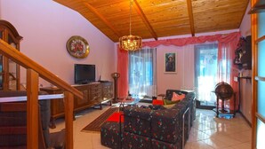 A living room with a wooden ceiling, a television, a sofa, and a dining area with a staircase. - House 1461/13494 (Istria - Pula), 4500m from the beach (Pula)