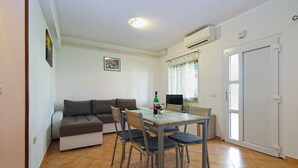 A compact living space with a sofa, dining table, chairs, a TV, and a door. - Apartment 1468/13511 (Istria - Fažana), 300m from the beach (Fažana)