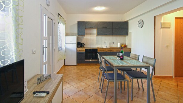 A compact kitchen with modern appliances, a dining area with a table and chairs, and a living area with a TV and a 'Welcome' sign. - Apartment 1468/13511 (Istria - Fažana), 300m from the beach (Fažana)