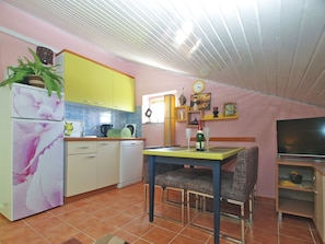 Una cocina funcional con armarios amarillos, un lavavajillas blanco y un comedor con mesa y sillas.