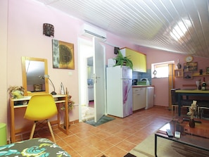 Un espacio habitable compacto con kitchenette, comedor y pequeña área de trabajo.