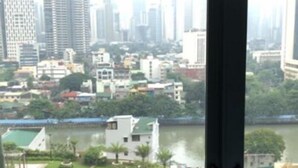 Vista desde un edificio alto sobre un paisaje urbano con un río, un edificio circular con techo verde y varios edificios más.