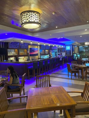 A restaurant interior with a bar area, wooden tables and chairs, and a ceiling with a decorative light fixture. - 2 bedroom condo available at Tivoli Garden Residences Luxury Resort makati (Metro Manila)