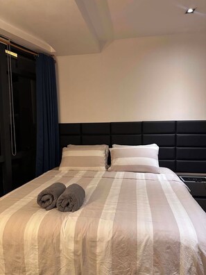 Une chambre d’hôtel comprenant un lit, deux oreillers, une tête de lit et un ensemble de serviettes.