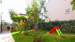A garden with a swing set, a slide, and a stone pathway. - Apartment 1482/13875 (Istria - Medulin), 600m from the beach (Medulin)