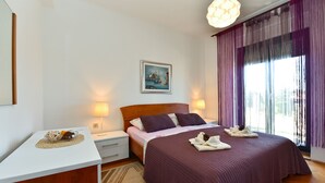 A bedroom with a bed, bedside lamps, a painting, and a window with curtains. - Apartment 1490/14261 (Istria - Fažana), 350m from the beach (Fažana)