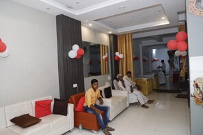 A hotel lobby with seating areas, a reception desk, and a decorative wall.