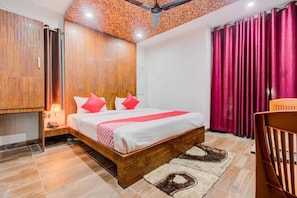 A bedroom with a wooden bed, a nightstand, a lamp, a ceiling fan, and a window with curtains.