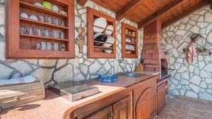 A rustic kitchen with stone walls, wooden shelves, and a built-in oven. - Apartment 1495/14369 (Istria - Banjole), 500m from the beach (Banjole)
