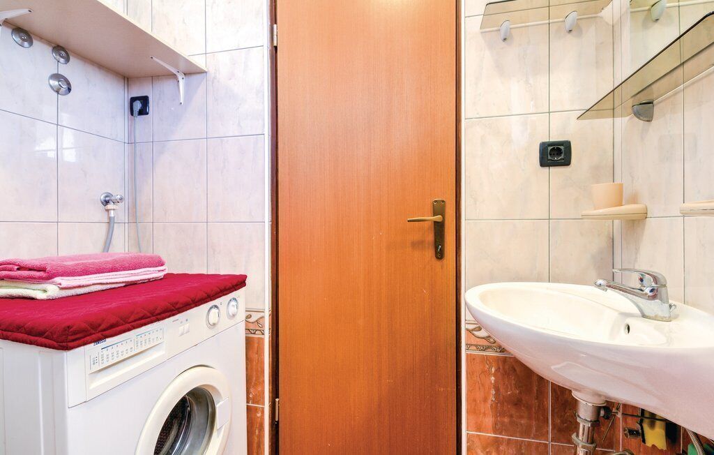 A bathroom with a washing machine, a wooden door, and a sink.
