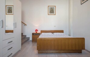 Ein Schlafzimmer mit einem hölzernen Bett, einem Nachttisch mit Lampe, einem Kleiderschrank und einer Treppe.