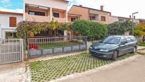 A residential area with a row of houses, a car parked in front, and a paved walkway.