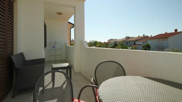 A balcony with wicker furniture, a glass door, and a view of neighboring houses.