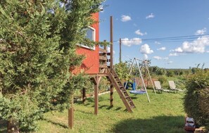 Un edificio rosso con una scala di legno che conduce a una finestra, circondato da vegetazione e un cielo sereno.