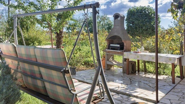Un espacio de estar al aire libre con una silla colgante y un patio de piedra.