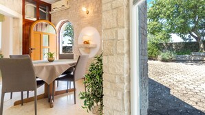 A dining area with a stone wall, a table with chairs, and a view of the outdoor courtyard.