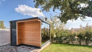 A modern outdoor sauna with a wooden exterior and glass walls, surrounded by a well-maintained garden and a clear sky. - Villa 1521/15241 (Istria - Žminj), 25000m from the beach (Žminj)