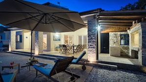 An outdoor patio area with lounge chairs, a table, and a large umbrella. - Villa 1521/15241 (Istria - Žminj), 25000m from the beach (Žminj)