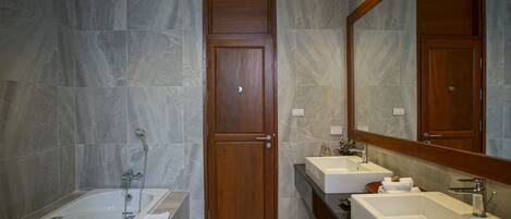 Un baño moderno con lavamanos doble, bañera y puerta de madera.