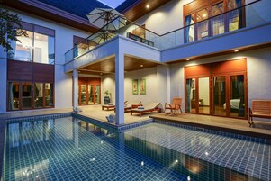 Uma casa moderna com uma grande piscina ao ar livre, um alpendre coberto e uma varanda no segundo andar.