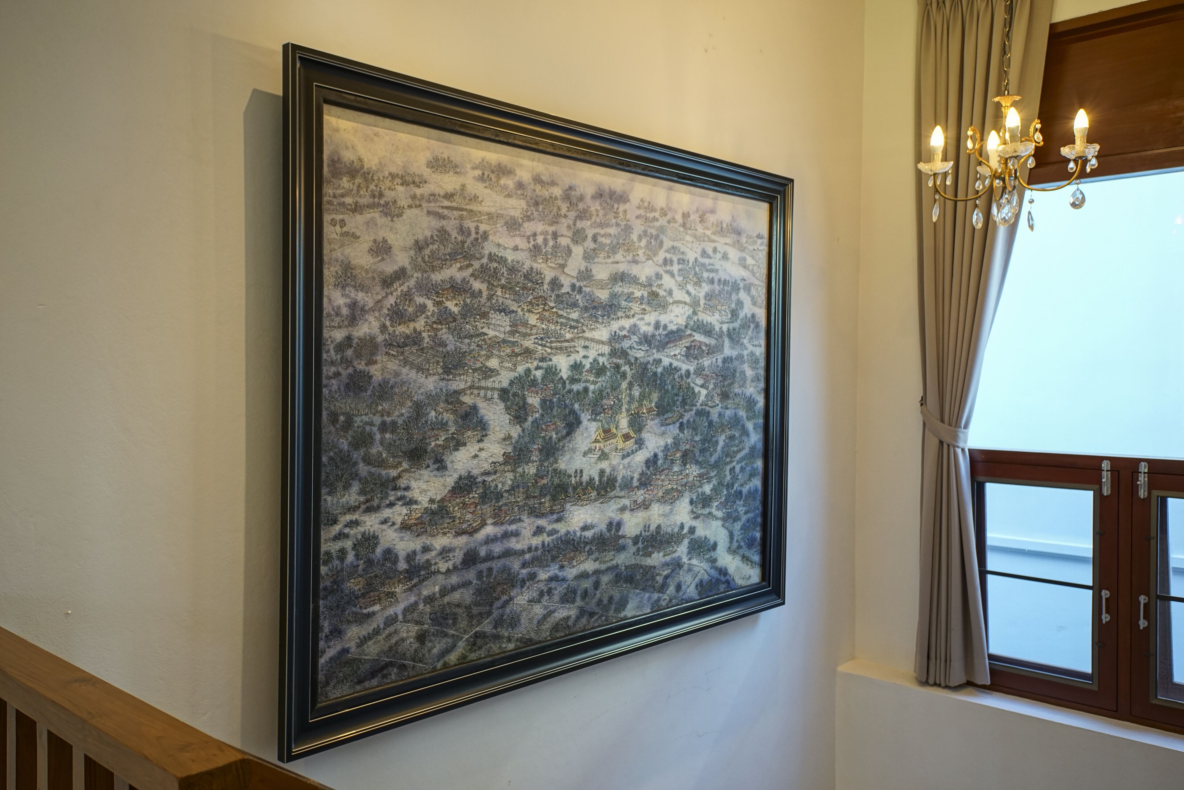 A framed landscape painting on a wall, a chandelier, and a window with curtains.