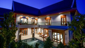 Una casa de varios pisos con piscina, mobiliario exterior y un patio cubierto.