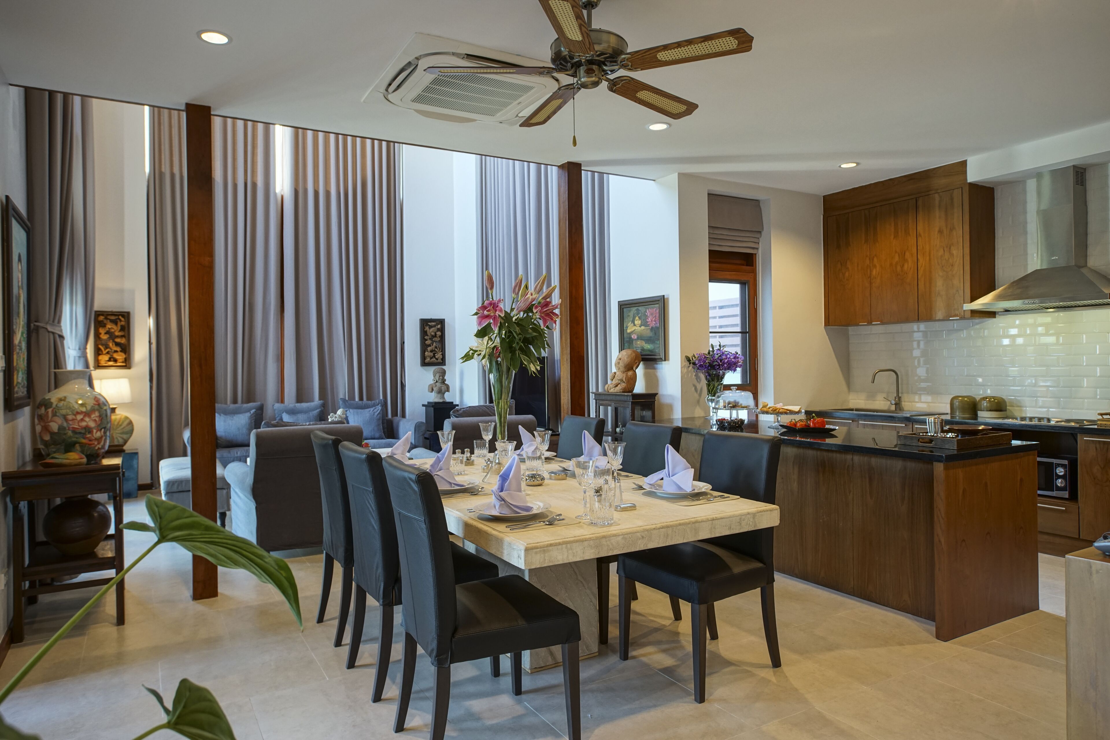 Une cuisine moderne dotée d’un îlot central, de meubles en bois et d’un coin repas avec une table dressée pour six personnes.