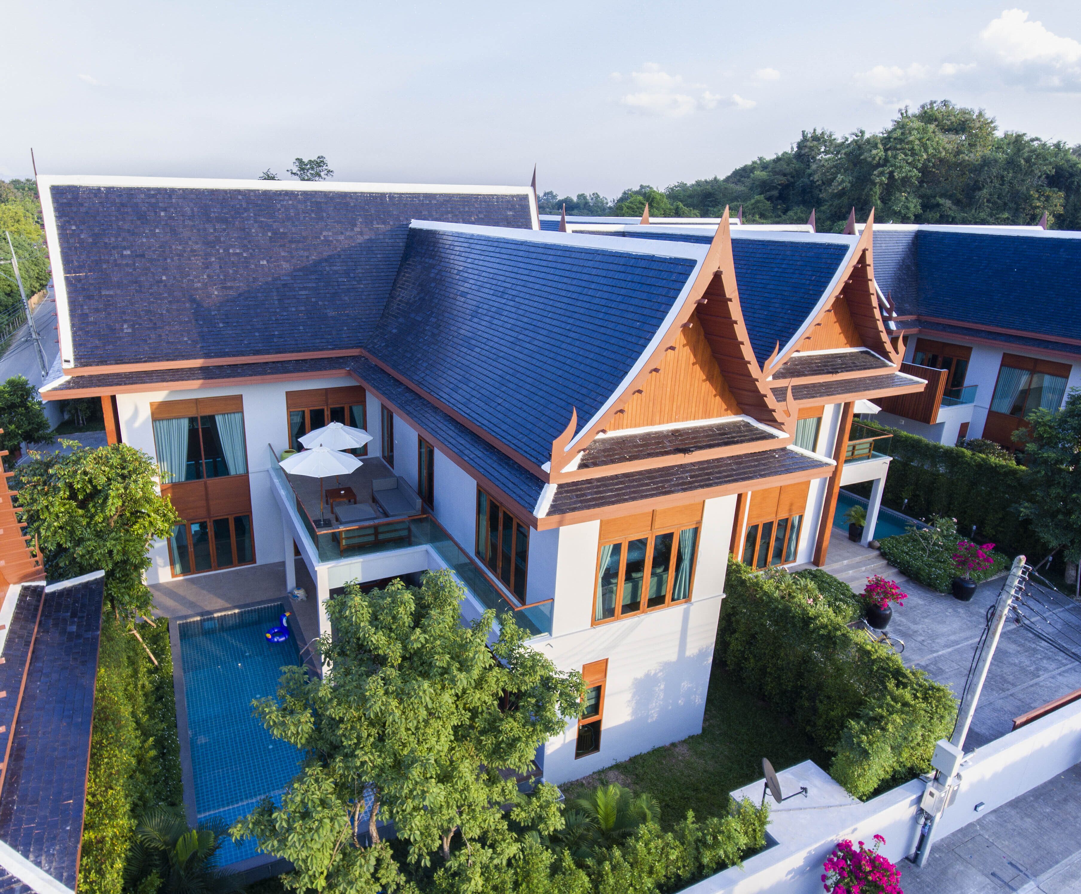 A modern building with multiple levels, a swimming pool, and lush greenery.
