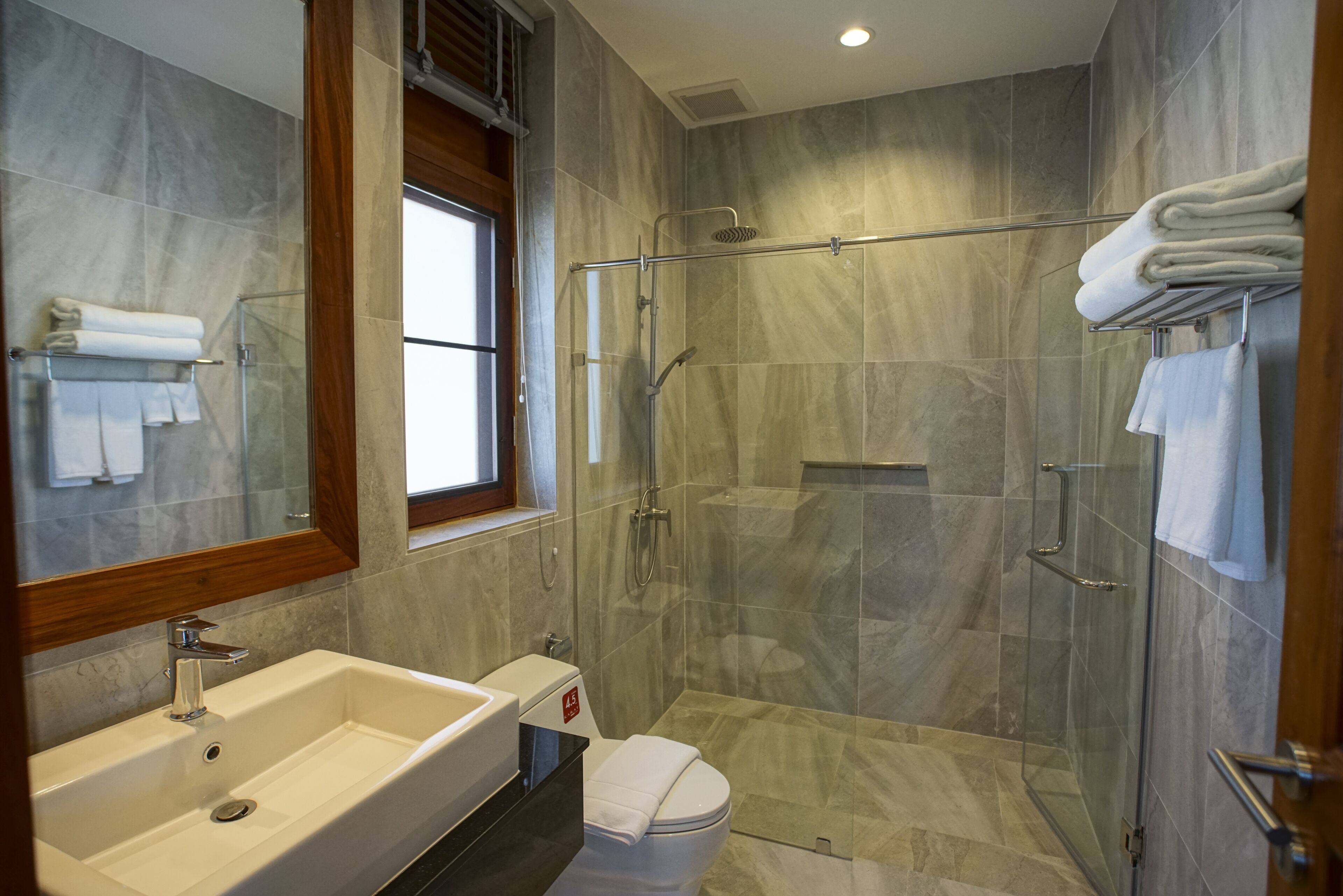 Un baño moderno con un lavamanos grande, inodoro y ducha a ras de suelo.