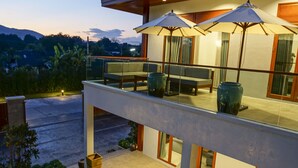 Una casa moderna con balcón, mobiliario exterior y piscina.