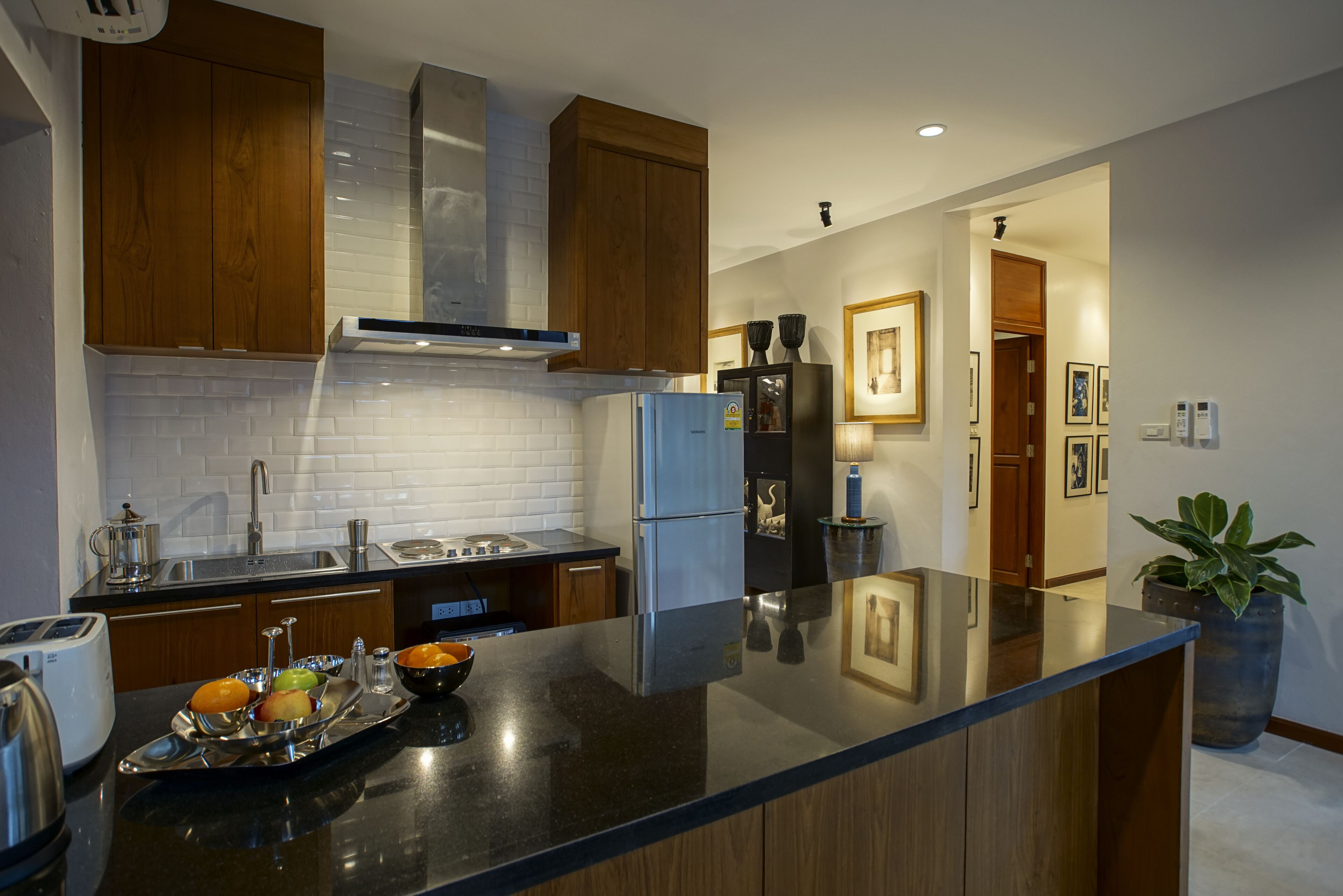 A modern kitchen with wooden cabinets, a stainless steel refrigerator, and a black countertop.
