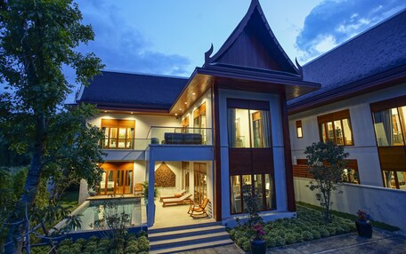 A modern two-story house with a large balcony, a swimming pool, and a well-maintained garden.