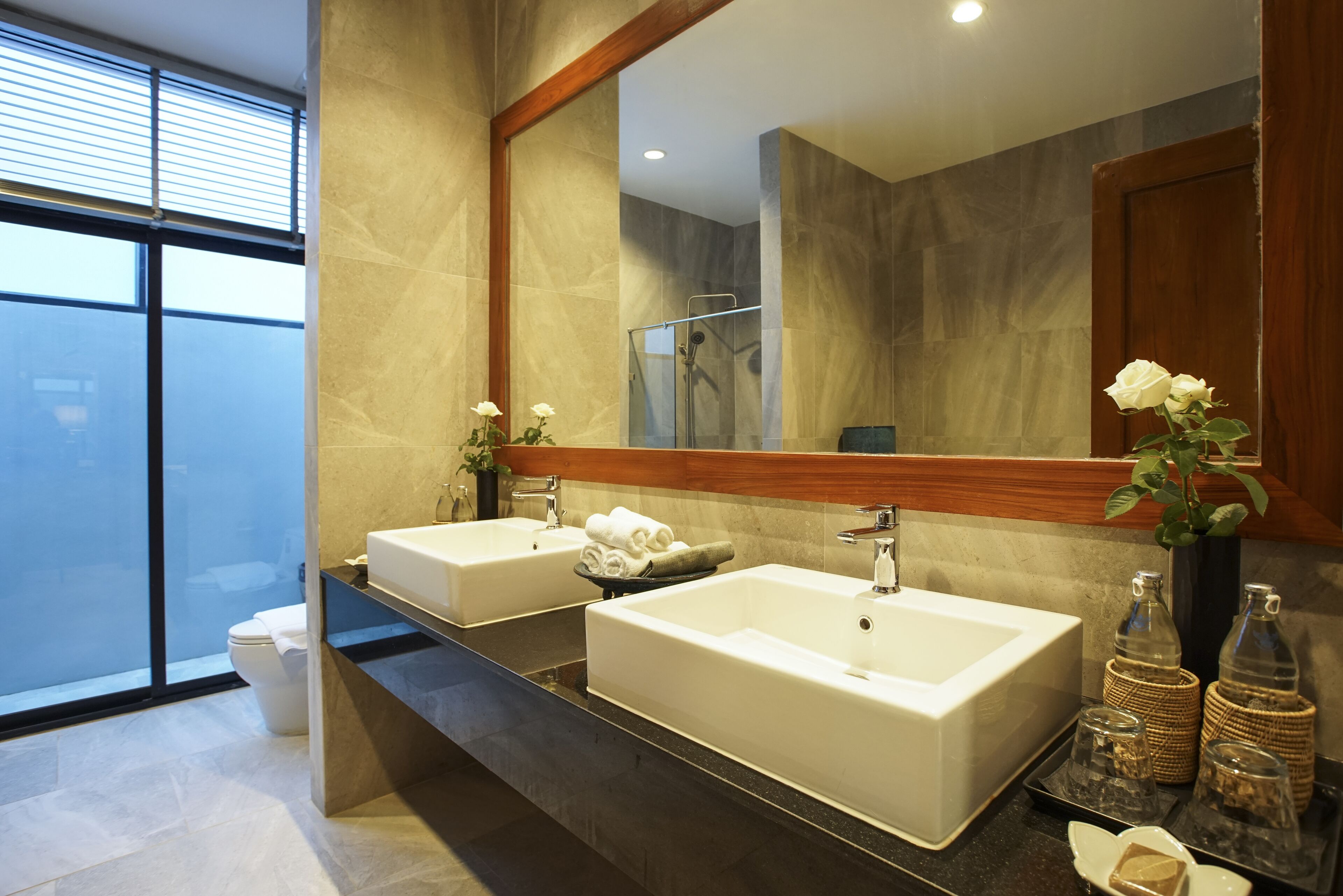 A modern bathroom with two sinks, a large mirror, and a shower.