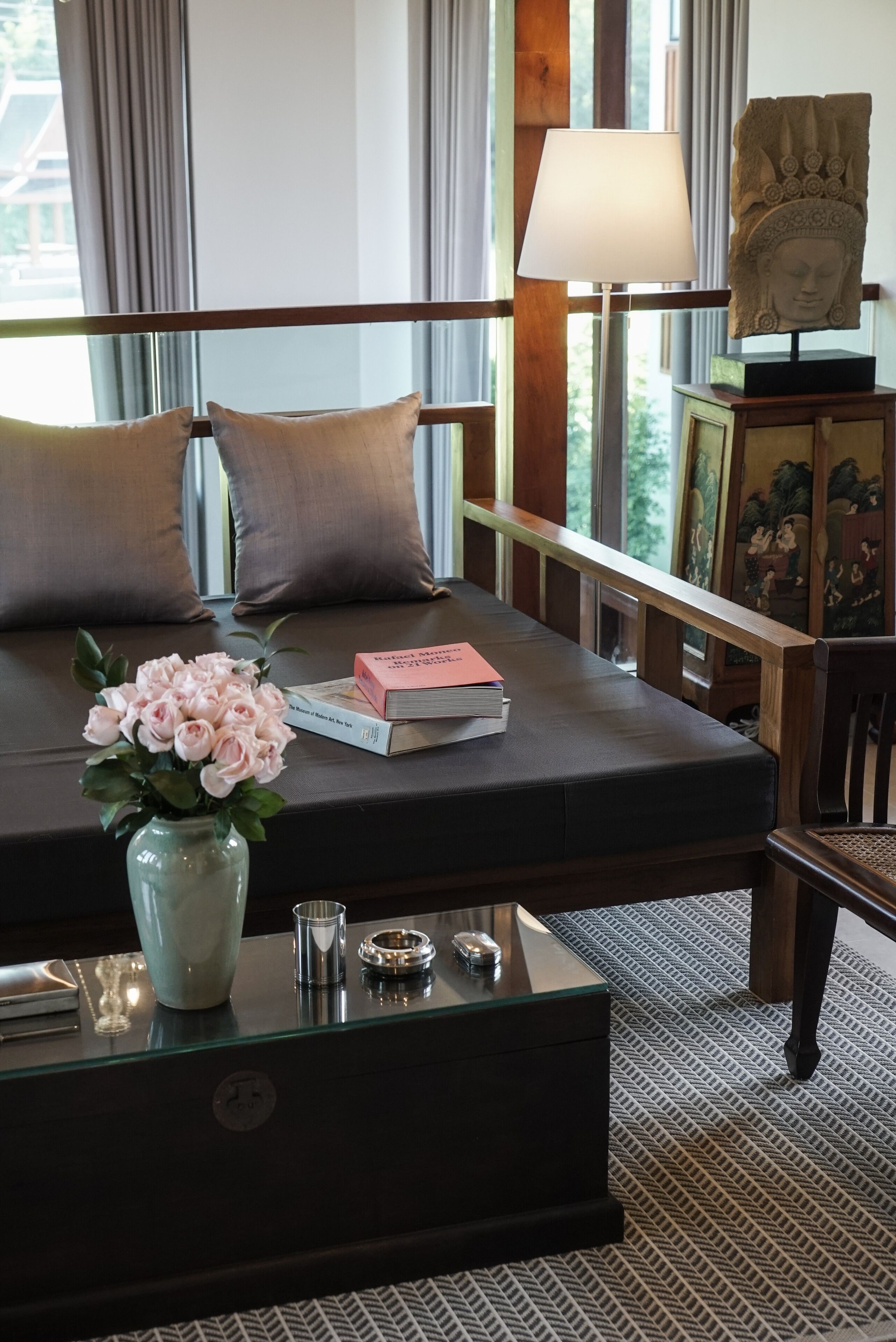 Une chambre d’hôtel bien aménagée, avec un canapé, un vase de fleurs, une lampe et un objet décoratif posé sur une table.