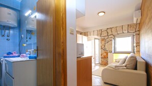 A compact living space with a kitchenette, a stone wall, and a sofa. - Apartment 1531/15377 (Istria - Vinkuran), 500m from the beach (Vinkuran)
