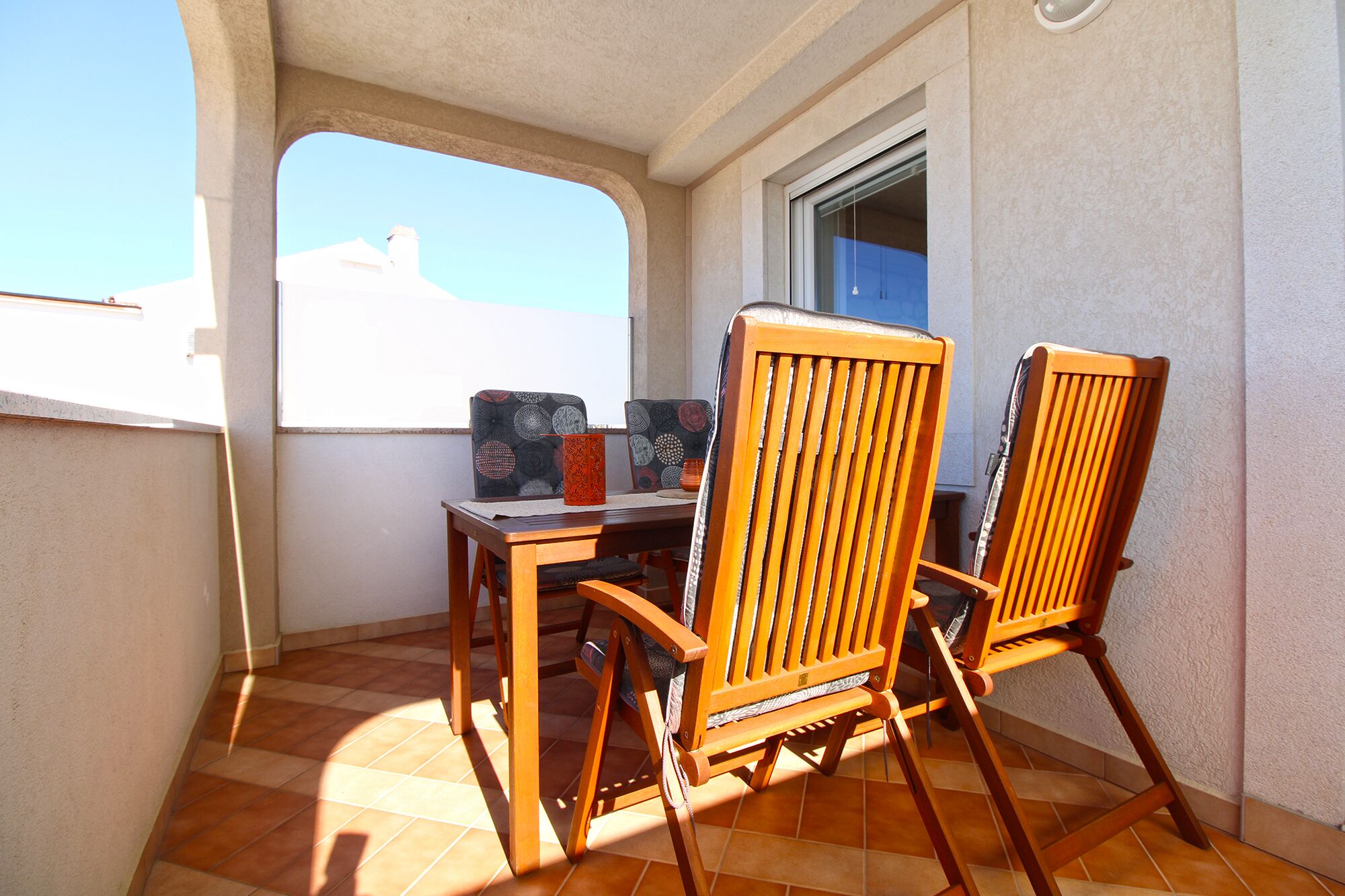 A balcony with two wooden chairs, a small table, and a window.