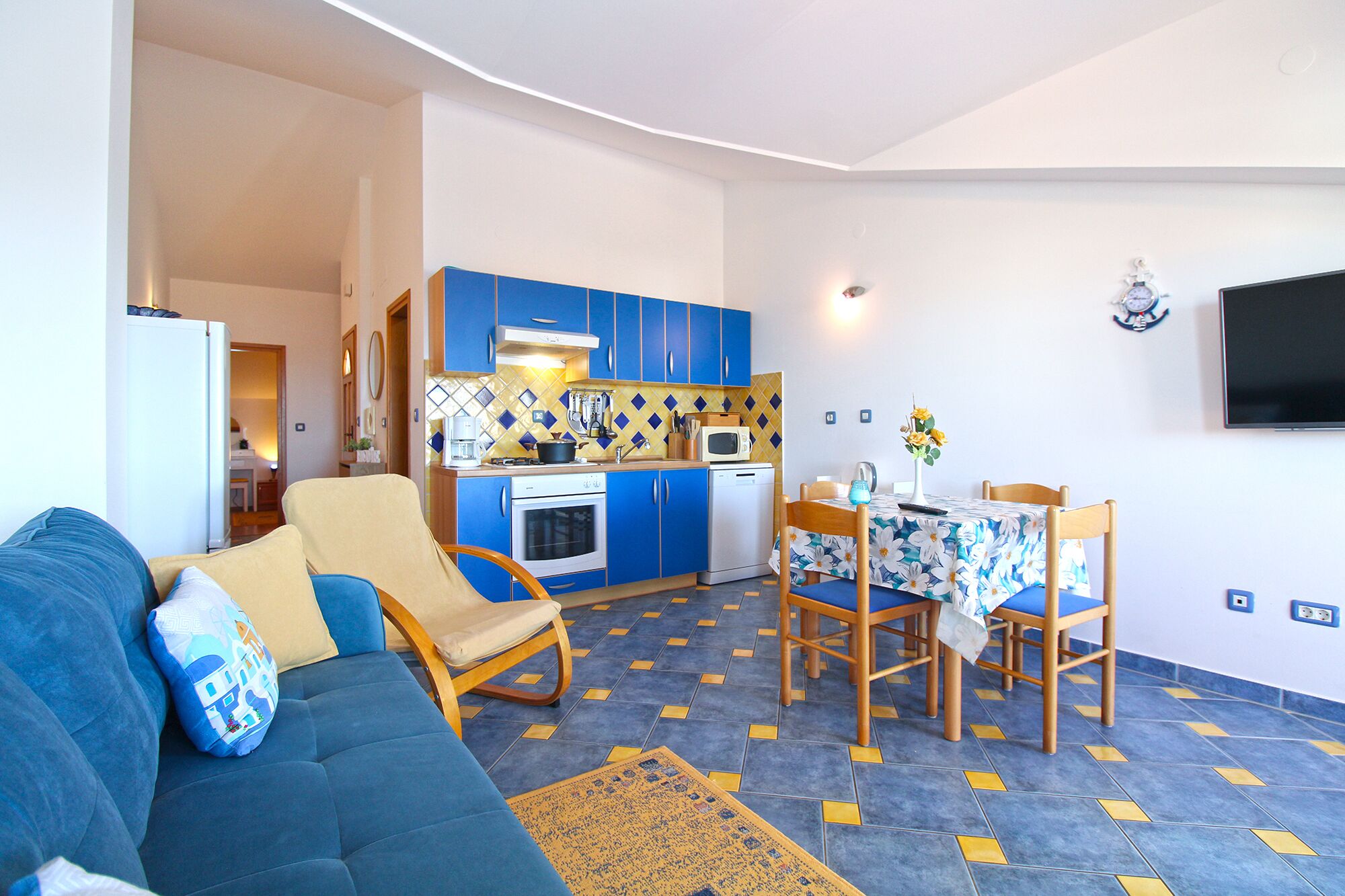Ett kompakt bostadsutrymme med ett litet kök, en matplats och en soffa.
