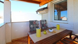 An outdoor patio with a wooden table and chairs, a yellow candle holder, and a potted plant. - Apartment 1531/15384 (Istria - Vinkuran), 500m from the beach (Vinkuran)