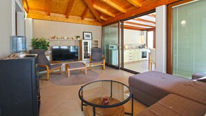 A modern living room with a television, seating, and a kitchen visible through a glass door. - Apartment 1531/15385 (Istria - Vinkuran), 500m from the beach (Vinkuran)