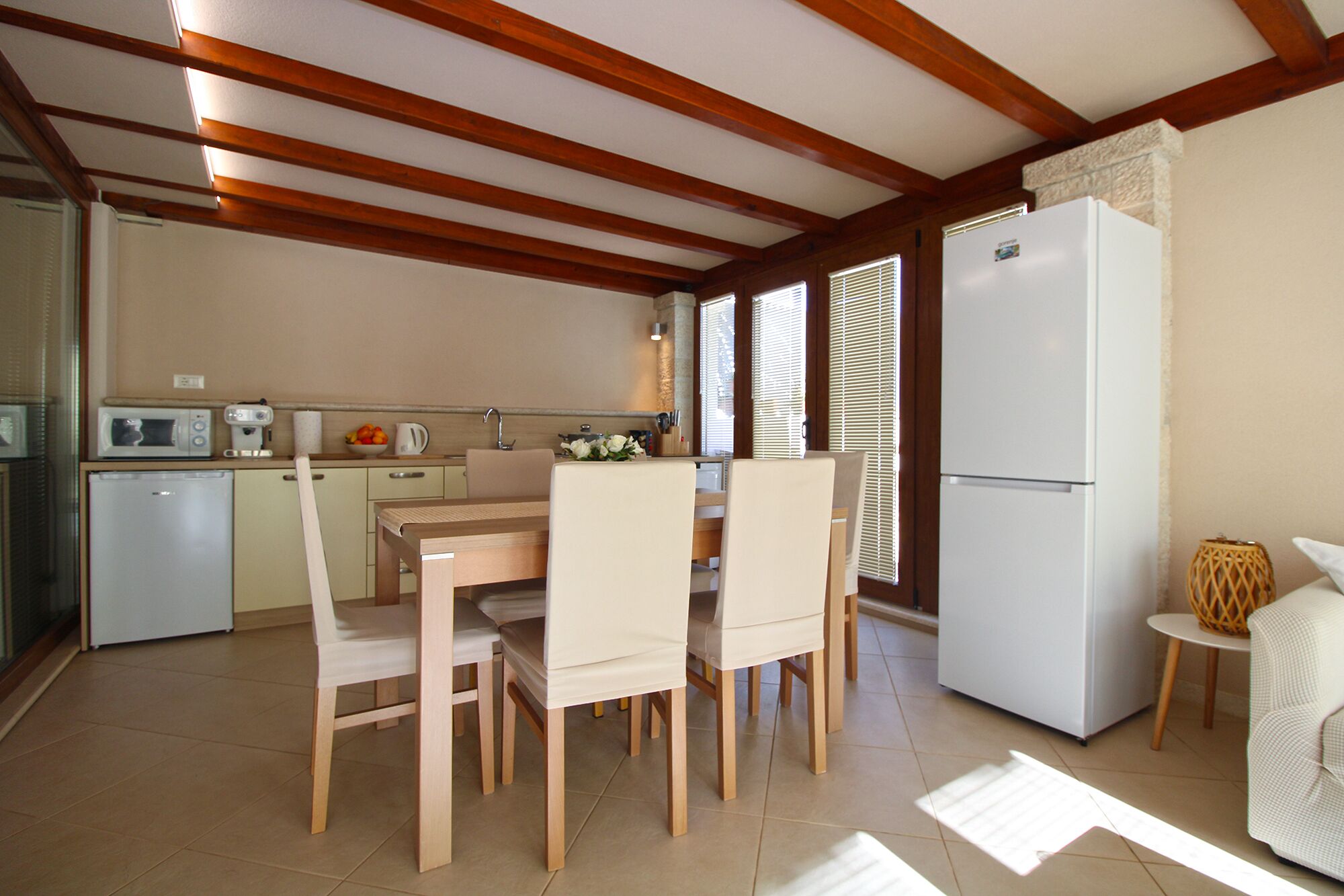 A compact kitchen with a dining table and chairs, a refrigerator, and a microwave.