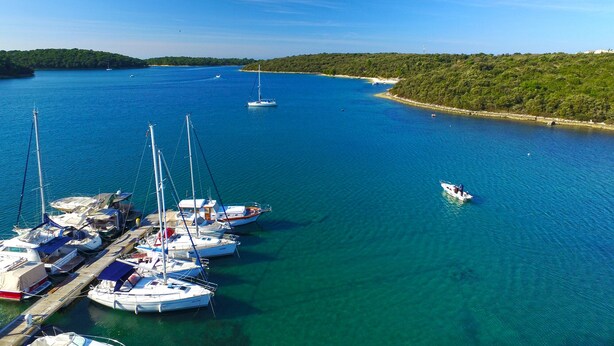 A marina with several sailboats docked, surrounded by clear blue water and a hilly landscape. - Apartment 1531/15385 (Istria - Vinkuran), 500m from the beach (Vinkuran)