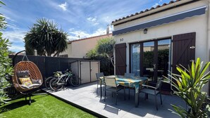 A patio with a table and chairs, a hanging chair, a shed, and a bicycle. - Air-conditioned house with pool, bikes and terrace 800 metres from the beach (Saint-Cyprien Plage)
