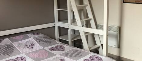A bunk bed with a ladder, a quilt with heart patterns, and a wall-mounted air conditioner.