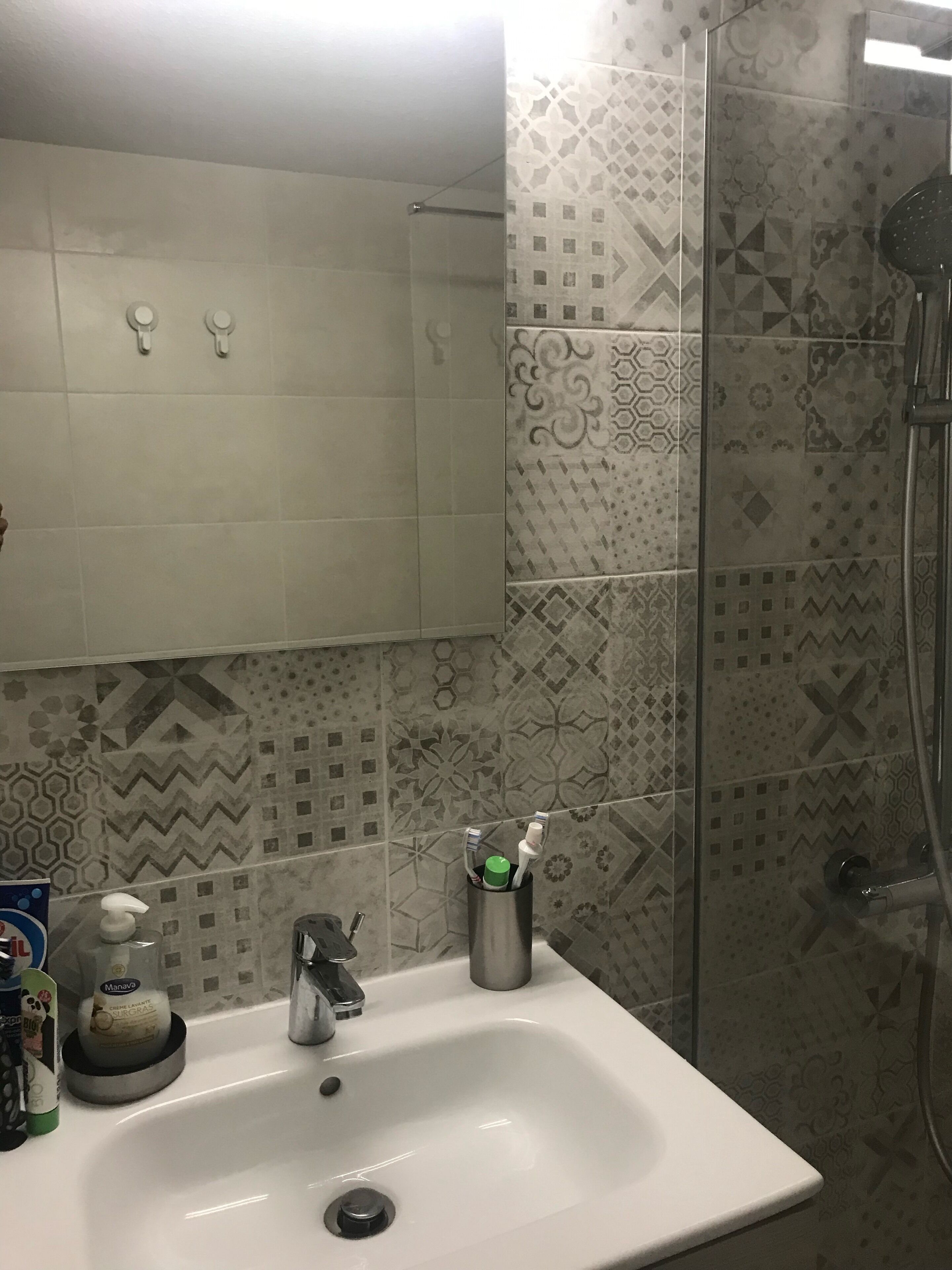 A bathroom with a white sink, a mirror, and a shower area.
