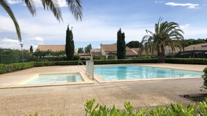 A swimming pool with a tiled deck, surrounded by greenery and palm trees. - Air-conditioned house with pool, bikes and terrace 800 metres from the beach (Saint-Cyprien Plage)