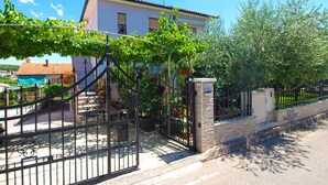 A house with a gated entrance, a stone wall, and a metal gate.