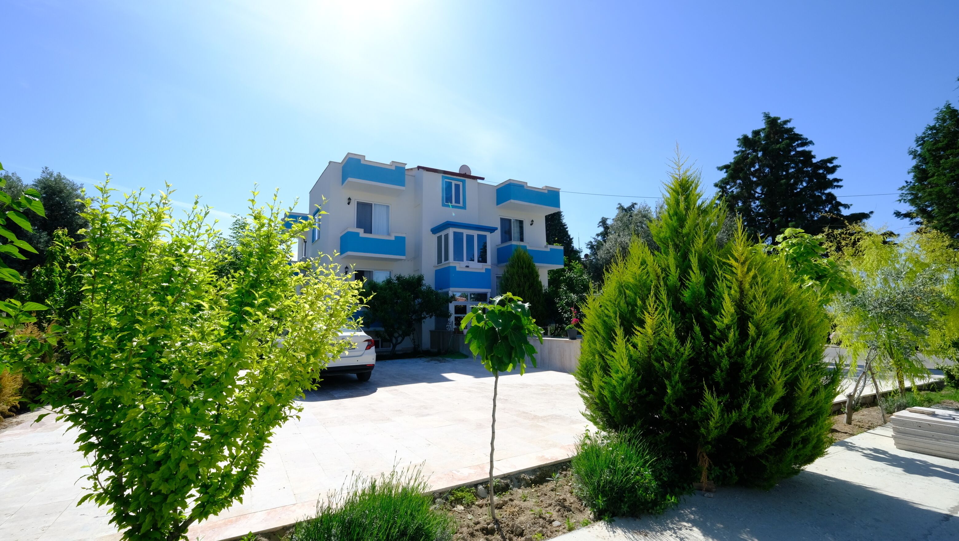 A two-story building with a blue and white exterior, a driveway, and surrounding greenery.