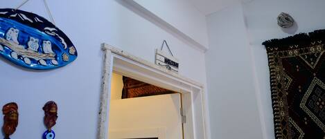 A doorway with a 'Welcome' sign, a patterned tapestry, and decorative items on the wall.